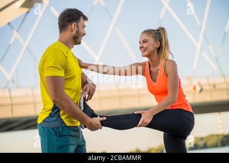 Un jeune couple fait de l'exercice en plein air. Ils s'étirent et s'échauffent pour le jogging. Banque D'Images