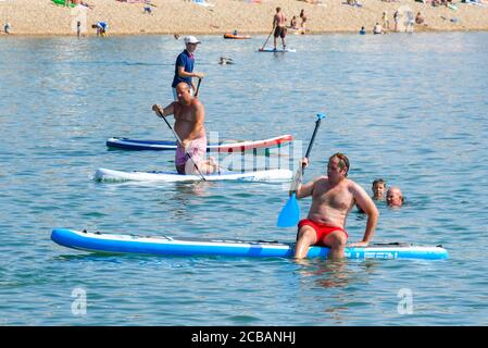 Lyme Regis, Dorset, Royaume-Uni. 12 août 2020. Météo Royaume-Uni. Paddle-boarders sur la mer calme à la station balnéaire de Lyme Regis à Dorset sur un autre jour chaud chaud chaud et ensoleillé que la vague de chaleur continue. Crédit photo : Graham Hunt/Alamy Live News Banque D'Images