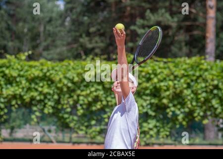 Un jeune joueur de tennis sert dans un jeu de tennis. Banque D'Images