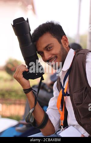 Jeune photographe souriant avec un appareil photo à portée de main Banque D'Images