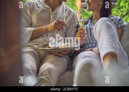 Souriant, deux personnes adorables se détendent tout en étant assis sur le canapé à l'extérieur Banque D'Images