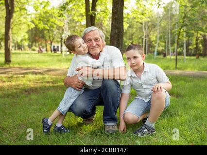 L'homme âgé et les petits-fils sont embrassant et souriants, se reposant ensemble