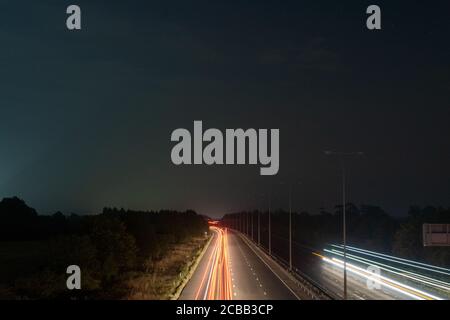des sentiers de circulation de nuit sur une autoroute traversant l' campagne Banque D'Images