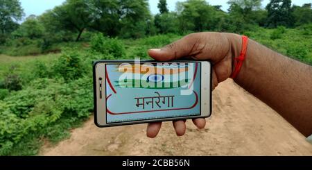 DISTRICT KATNI, INDE - 18 SEPTEMBRE 2019: Mahatma Gandhi National Rural Employment Guarantee Act logo affiché sur l'écran du smartphone par indian vill Banque D'Images