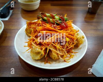 Bibim Mandu ou Bibim Mandoo. Boulettes mixtes de style coréen. Potstickers poêlés mélangés à de la salade et une sauce sucrée, acidulée et épicée addictive. Banque D'Images