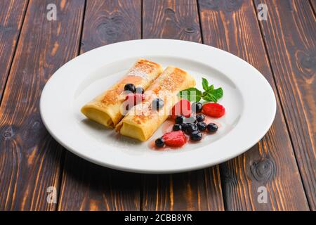 Assiette de fines crêpes farcies au lait caillé et servies avec confiture de baies Banque D'Images