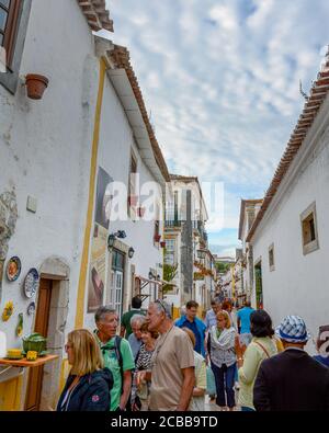 Obidos, Portugal - 16 mai 2017 : touristes marchant dans les rues étroites en pierre de galets de la belle ville d'Obidos au Portugal. Banque D'Images