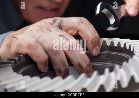 Réparateur avec mains sales travaillant avec une clé et un molette cog - mise au point sélective sur la main Banque D'Images