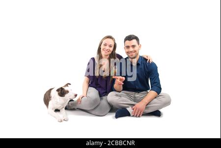 Portrait de famille d'un jeune couple avec chien et perroquet sur blanc pur Banque D'Images