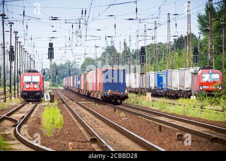 10 août 2020, Brandebourg, Wustermark : un train de marchandises tiré par une locomotive électrique de Hamburger Hafen und Logistik AG (HLA) passe la gare dans le village de Priort. Deux trains vous attendent sur la gauche. Photo: Soeren Stache/dpa-Zentralbild/ZB Banque D'Images