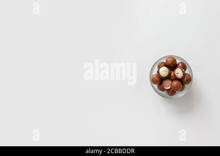 Noix de macadamia dans un bol en verre sur fond gris design pour poster, article ou bannière Banque D'Images