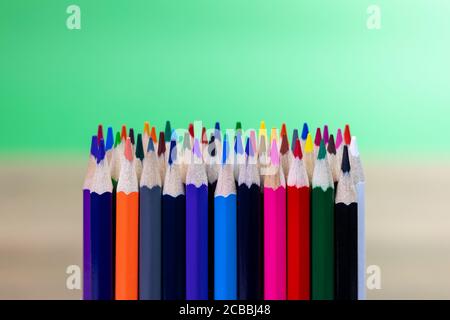 gros plan des crayons de couleur alignés verticalement avec le vert et sur fond beige Banque D'Images