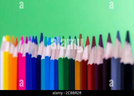 gros plan des crayons de couleur alignés verticalement avec un arrière-plan vert Banque D'Images