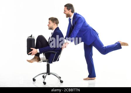 Homme en costume poussant la chaise avec colegue on. Deux hommes d'affaires passent avec force leur temps de travail au bureau, isolés sur fond blanc. Banque D'Images