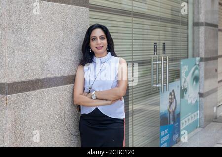 Une femme indienne debout avec ses armes a traversé un cadre urbain d'entreprise. Femme d'entreprise en tenue habillée élégante Banque D'Images