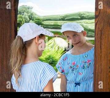 petite fille devant un miroir de distorsion. miroir de funhouse dans un parc Banque D'Images