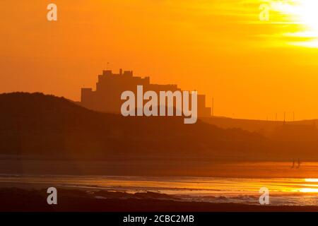 Coucher de soleil sur le château et la plage de Bamburgh, Bamburgh, Northumberland, Royaume-Uni. Banque D'Images