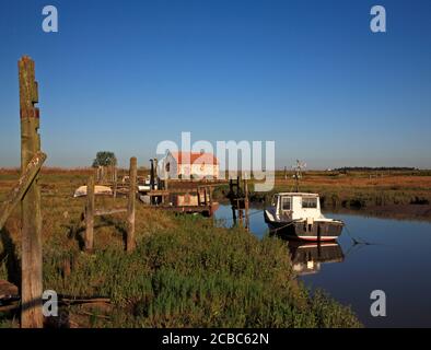 Vue sur le port et le quai avec des bateaux et l'ancienne Barn de charbon sur la côte nord de Norfolk à Thornham, Norfolk, Angleterre, Royaume-Uni. Banque D'Images