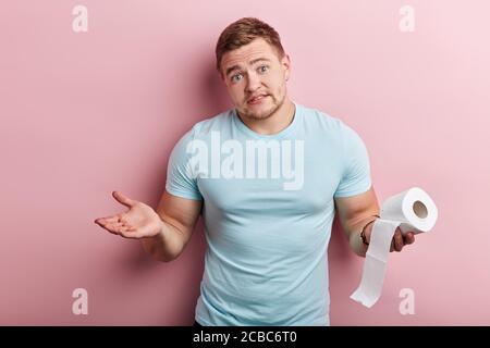 malheureux homme sérieux holdong toliet tissus et regardant la caméra avec l'expression sans indice, situation inplesante Banque D'Images