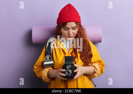 Jeune femme attrayante touriste avec appareil photo et sac à dos, isolé sur fond bleu, passe-temps, intérêt, style de vie, gros plan portrait Banque D'Images