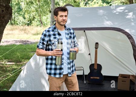 Boissons touristiques thé près du camping tente dans une forêt Banque D'Images