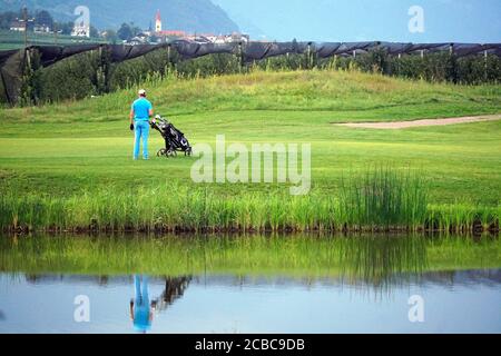 Golfeur avec voiturette de golf regardant un partenaire au club de golf Blue Monster dans le sud du Tyrol, Italie. Banque D'Images