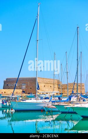 Port de plaisance d'Héraklion. Yachts à voile avec de hauts mâts dans le port près de la forteresse vénitienne le jour ensoleillé d'été, île de Crète, Grèce Banque D'Images