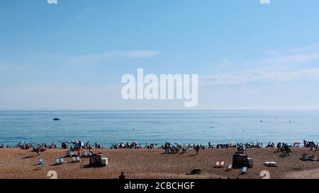 Brighton, Royaume-Uni - 10 août 2020 : beaucoup de gens sur la plage et dans la mer en profitant du temps chaud. Banque D'Images