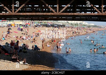 Brighton, Royaume-Uni - 10 août 2020 : beaucoup de gens sur la plage et dans la mer en profitant du temps chaud. Banque D'Images