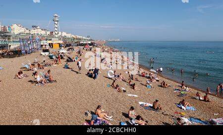 Brighton, Royaume-Uni - 10 août 2020 : beaucoup de gens sur la plage et dans la mer en profitant du temps chaud. Banque D'Images