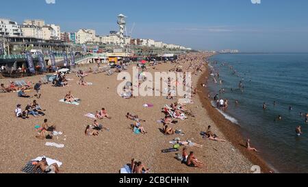 Brighton, Royaume-Uni - 10 août 2020 : beaucoup de gens sur la plage et dans la mer en profitant du temps chaud. Banque D'Images