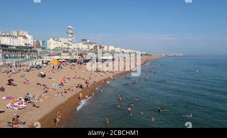Brighton, Royaume-Uni - 10 août 2020 : beaucoup de gens sur la plage et dans la mer en profitant du temps chaud. Banque D'Images
