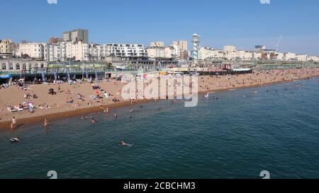 Brighton, Royaume-Uni - 10 août 2020 : beaucoup de gens sur la plage et dans la mer en profitant du temps chaud. Banque D'Images
