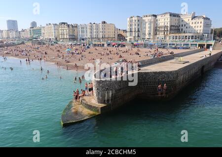 Brighton, Royaume-Uni - 10 août 2020 : beaucoup de gens sur la plage et dans la mer en profitant du temps chaud. Banque D'Images