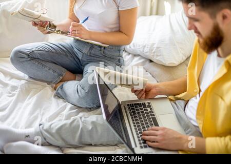 heureux couples caucasiens mariés triant des lettres à la maison, ils vont inviter des invités dans leur nouvelle maison, houseewarming. ils font des notes sur ordinateur portable et pr Banque D'Images