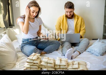 beau caucasien couple marié triant des lettres à la maison, ils planifient le mariage dans le mois futur, va envoyer des invitations à des amis et des parents. assis Banque D'Images