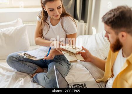 beau caucasien couple marié triant des lettres à la maison, ils planifient le mariage dans le mois futur, va envoyer des invitations à des amis et des parents. assis Banque D'Images