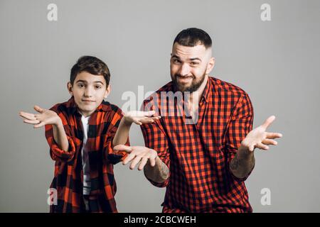 quel est notre problème. Homme beau et fils confus et perplexe debout avec les mains écartés dans une posture sans indice. Gros plan. Fans regardant un match. e Banque D'Images