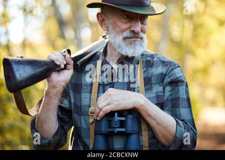 Portrait d'un chasseur senior ouvert avec une arme sur les épaules Banque D'Images