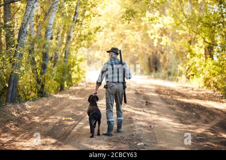 Chasseur senior tenant le chien après la chasse sur les canards. Vue arrière de Hunter Banque D'Images