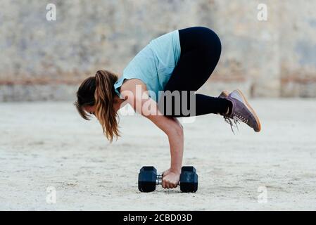 Jeune femme qui fait des positions de yoga en milieu urbain. Banque D'Images