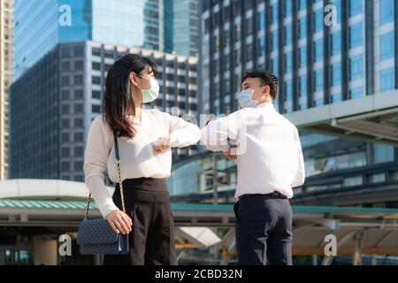 Le relief du coude est une nouvelle salutation nouvelle pour éviter la propagation du coronavirus. Deux amis d'affaires asiatiques se rencontrent devant le bureau. Au lieu de saluer Banque D'Images