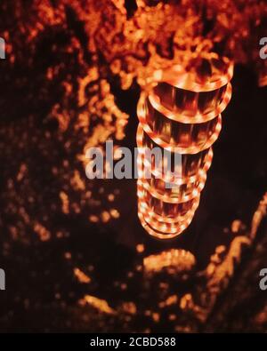 Une spirale de rouge vif et de lumières de Noël claires réfléchissantes Dans une piscine d'eau Banque D'Images