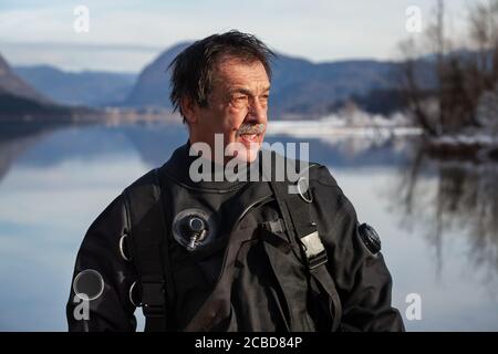 Plongeur mature dans une combinaison sèche après une plongée de sauvetage Un lac froid glacial Banque D'Images