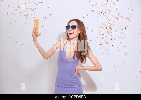 Jolie jeune femme asiatique debout et prenant un selfie isolé sur fond blanc. Banque D'Images