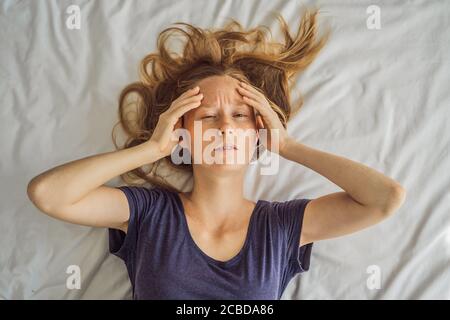 Jeune femme extrêmement fatiguée, couché sur le lit, à la maison seule. Auto-isolement à la maison, quarantaine en raison de la pandémie COVID 19. Problèmes de santé mentale en soi Banque D'Images