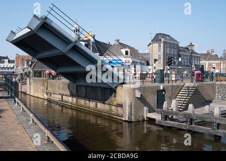 Le Blokjesbrug, un pont-levis à Lemmer, est en train de monter. Les gens attendent derrière la barrière fermée lors d'une journée ensoleillée et chaude Banque D'Images