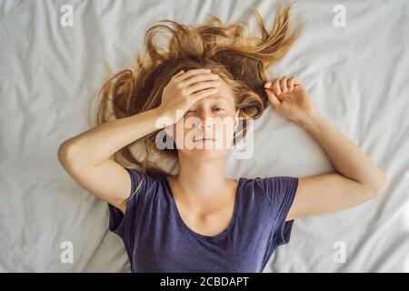 Jeune femme extrêmement fatiguée, couché sur le lit, à la maison seule. Auto-isolement à la maison, quarantaine en raison de la pandémie COVID 19. Problèmes de santé mentale en soi Banque D'Images