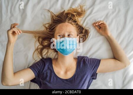 Jeune femme extrêmement fatiguée, couché sur le lit, à la maison seule. Auto-isolement à la maison, quarantaine en raison de la pandémie COVID 19. Problèmes de santé mentale en soi Banque D'Images