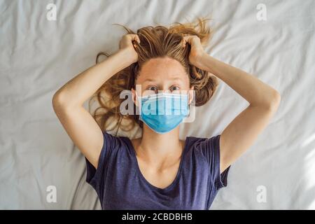 Jeune femme extrêmement fatiguée, couché sur le lit, à la maison seule. Auto-isolement à la maison, quarantaine en raison de la pandémie COVID 19. Problèmes de santé mentale en soi Banque D'Images